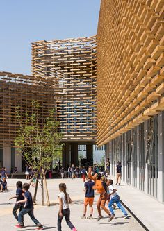 children are playing outside in front of a building that has wooden slats on it