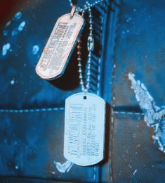 a dog tag is hanging from a chain on a piece of metal that has been scratched