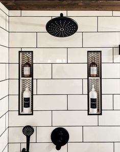 two black and white faucets mounted to the side of a tiled shower wall