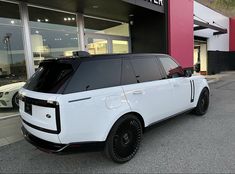 a white range rover is parked in front of a car dealership with its doors open