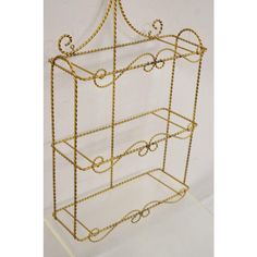 a gold metal shelf with three shelves on each side and two hanging hooks at the top