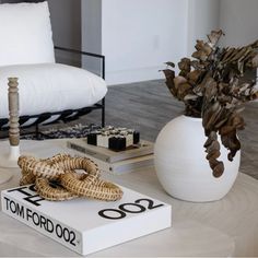 a white table topped with books and a vase filled with flowers on top of it