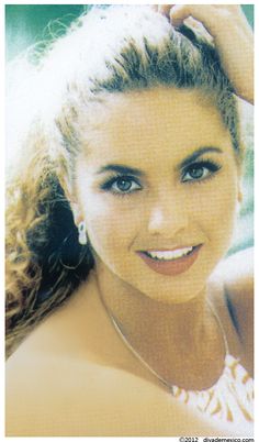 a close up of a person wearing a necklace and smiling at the camera with her hair pulled back