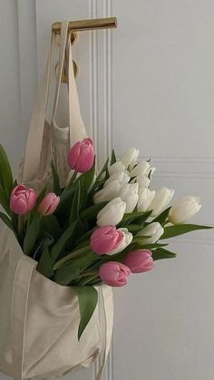 a white bag with pink and white tulips hanging from the front door handle