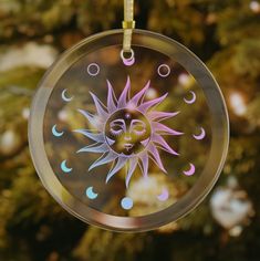 a glass ornament with a sun and moon design hanging from it's side