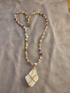 This necklace features a beautiful shard of surf tumbled pottery found on a beach in Puerto Rico. It is wrapped in brass colored copper wire. The beads are AAA quality aquamarine, abalone shell and dyed freshwater pearls. Beach Spiritual Hand Wrapped Necklaces, Hand Wrapped Spiritual Necklaces For The Beach, Spiritual Hand Wrapped Necklaces For Beach, Spiritual Hand Wrapped Necklace For Beach, Bohemian Shell Necklace With Gemstone Beads, Bohemian Amber Jewelry For Beach, White Bohemian Pendant Necklaces, Gold Hand Wrapped Amulet Necklace, Gold Amulet Style Hand Wrapped Necklace