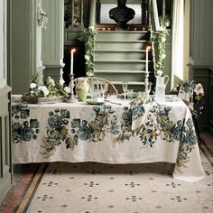 the table is set with candles and plates on it, along with greenery garlands