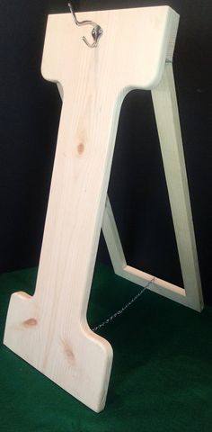 a wooden letter that is sitting on a green surface with chains hanging from it's sides