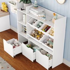 a white book shelf filled with lots of books and other items on top of a wooden floor