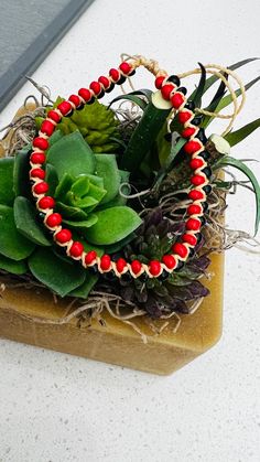 a succulent and beaded bracelet sits on top of a rock