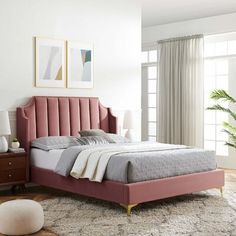 a bed with pink headboard and foot board in a white room next to a window