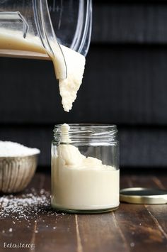 a person pouring milk into a glass jar