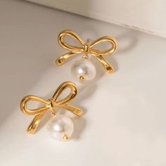 Introducing our Bow Pearl Earrings, a must-have accessory for any fashion-forward individual. With a super cute bow design and luxurious pearls, these earrings add a touch of girly charm to any outfit. Embrace the latest trend with these exclusive earrings. Made to last! Non Tarnish and Water Resistant, Hypoallergenic .78" Long 18K Gold Plated over 316L Stainless Steel base Chic Pearl Earrings As Gift, Chic Pearl Earrings For Gift, Trendy Bow Drop Earrings, Cute Bow Earrings For Wedding, Trendy Pearl Charm Earrings For Party, Trendy Pearl Charm Earrings For Gift, Trendy Pearl Drop Earrings As Gift, Trendy Pearl Earrings For Party, Gold Pearl Earrings With Bow For Gift