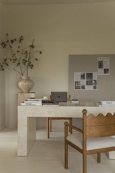 a desk with a chair and laptop on it in a room that has white walls