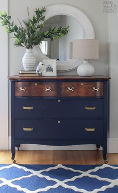 a blue dresser with a mirror and plant on it in front of a white door