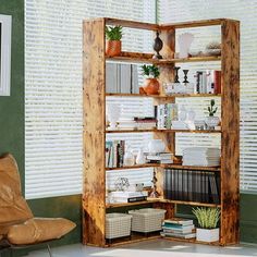 a wooden book shelf sitting in the corner of a living room next to a leather chair