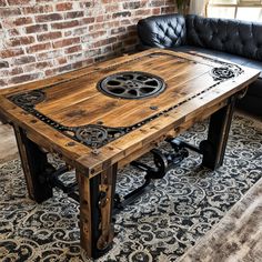 a wooden table with wheels on it sitting in front of a black leather couch and brick wall