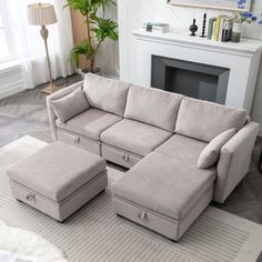 a living room with a sectional couch and ottoman in front of a white fire place