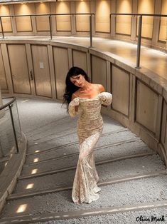 a woman in a long dress is standing on some stairs and posing for the camera