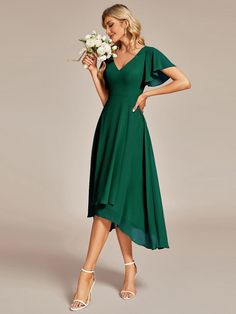 a woman in a green dress holding flowers