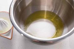 a metal bowl filled with liquid next to a whisk on top of a counter