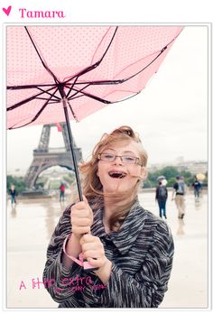 a woman with glasses holding an umbrella in front of the eiffel tower, paris