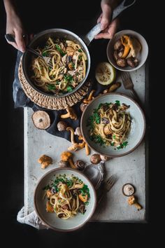 two bowls of pasta with mushrooms and parmesan cheese on the side, being served