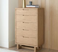 a wooden chest of drawers sitting next to a wall with books on top of it