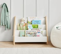 a bookshelf filled with children's books next to a coat rack and stuffed animal