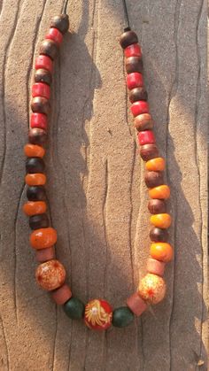 This slip-on, warm tone, wood bead necklace has a hippy feel to it.  It is made with mostly repurposed beads strung on a waxed black cord.  There are three accent beads, two of which have a red and cream floral pattern, the third of which has a dramatic red, cream, and orange stylized flower pattern. Cheap Orange Necklaces With Wooden Beads, Orange Wooden Beads For Festival, Orange Wooden Beads For Festivals, Brown Wooden Beaded Necklaces For Festivals, Bohemian Orange Necklaces With Wooden Beads, Bohemian Orange Necklace With Wooden Beads, Brown Fair Trade Necklace For Festival, Hippie Brown Beaded Necklace With Wooden Beads, Large Brown Beads For Festival