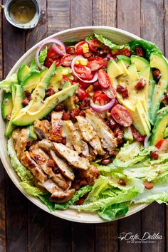 a salad with chicken, lettuce, tomatoes and avocado