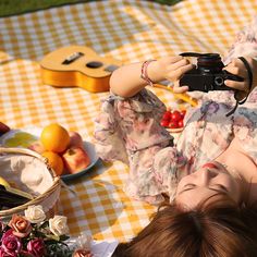 a woman laying on a picnic blanket holding a camera