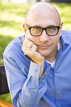 a bald man with glasses sitting on a bench