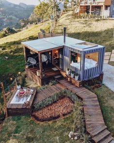 a small house made out of shipping containers on the side of a hill with stairs leading up to it