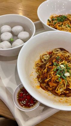 three bowls filled with food on top of a wooden table