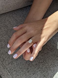 a woman's hand with a diamond ring on her left hand, sitting on the ground