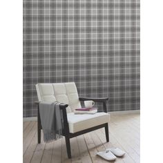 a white chair sitting in front of a wall with grey and white plaid pattern on it