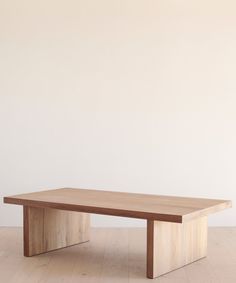 a wooden table sitting on top of a hard wood floor next to a white wall