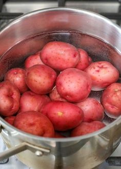 a pot full of red potatoes sitting on top of a stove next to a burner