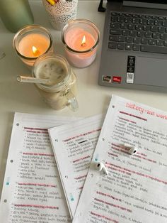 two notebooks sitting on top of a table next to a laptop computer and candles