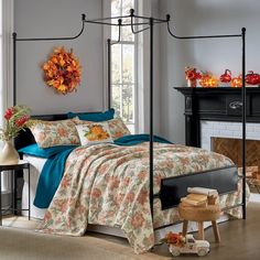 a bedroom with a four post bed and fireplace in the corner, decorated for fall