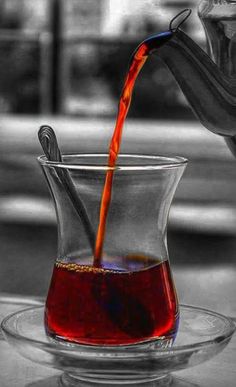 a red liquid being poured into a glass cup