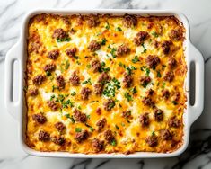 a casserole dish with meatballs and cheese in it on a marble surface