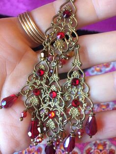 "These Antique Brass Filigree Moroccan Boho Chandelier Earrings are made with brass filigrees tiered to form a beautiful classic chandelier shape. Colorful crystal beads hang on each tier. Swarovski rhinestones add a touch of sparkle! Available with Posts, Clip-Ons, Leverbacks or French Wires. -4 1/2\" Long x 1 3/4\" Wide -0.4 oz. ea. Metal Finishes Available: -Antiqued Brass (as pictured) -Aged Bronze -Silver *As seen in the video Images show the 'Peacock Teal and Garnet', 'Ruby Red' & 'Bla Indian Peacock, Peacock Teal, Boho Chandelier, Moroccan Boho, Classic Chandeliers, Classic Chandelier, Antique Filigree, Brass Filigree, Garnet Crystal