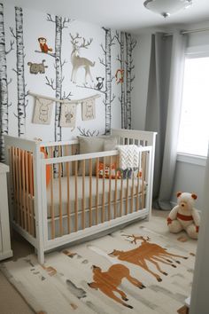 a baby's room decorated in white, orange and gray with deer wallpaper