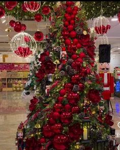 a christmas tree decorated with red and gold ornaments in a department store, surrounded by other holiday decorations