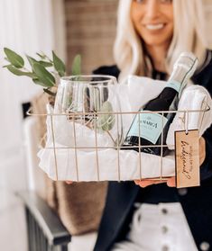 a woman holding a basket filled with bottles and glasses