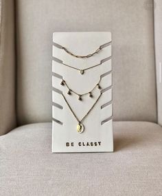 a card with three different necklaces on it sitting on a couch in front of a chair