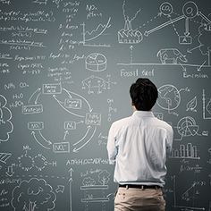 a man standing in front of a blackboard with lots of diagrams written on it