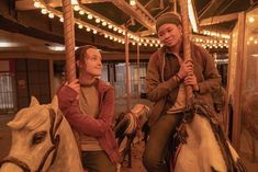 two young people riding on the back of a merry go round at an amusement park